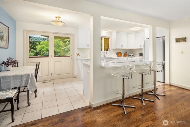 23318 3rd Pl W, Bothell, WA 98021 - kitchen featuring light countertops, white cabinets, light wood finished floors, a kitchen bar, and freestanding refrigerator