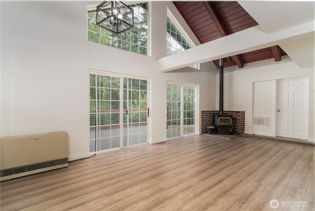 21405 Thompson Creek Rd SE, Tenino, WA 98589 - unfurnished living room with a chandelier, wood finished floors, a wood stove, high vaulted ceiling, and a wood ceiling with exposed beams