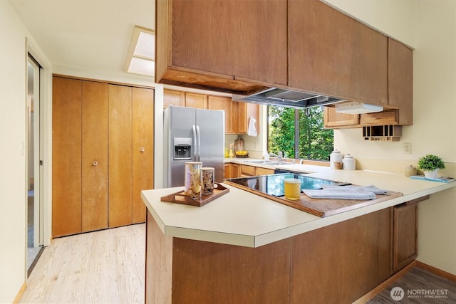 3909 Fielding Ave, Bellingham, WA 98229 - kitchen featuring stainless steel fridge, a peninsula, light wood-type flooring, light countertops, and black electric stovetop