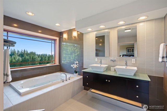 bathroom featuring double vanity, a jetted tub, tile patterned flooring, recessed lighting, and tile walls
