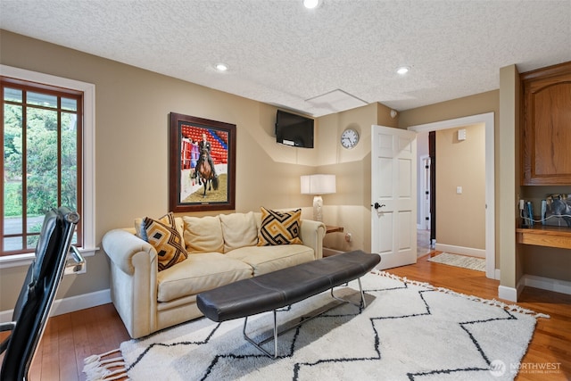 living room featuring a textured ceiling, recessed lighting, and light wood-style floors