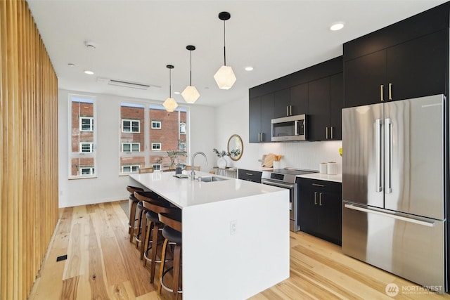 511 Howe St Unit C, Seattle, WA 98109 - kitchen featuring stainless steel appliances, dark cabinets, light countertops, light wood-type flooring, and recessed lighting