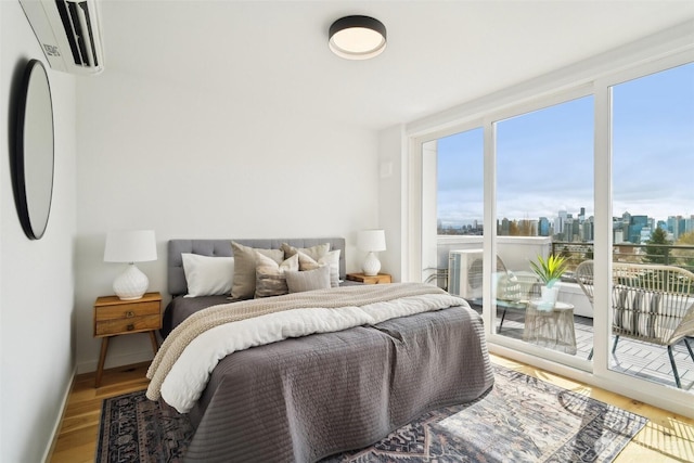 511 Howe St Unit C, Seattle, WA 98109 - bedroom featuring a wall unit AC, access to outside, a view of skyline, and wood finished floors