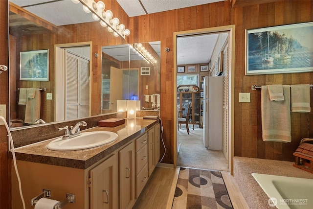 4925 Goodpiper Ln, Freeland, WA 98249 - full bathroom featuring vanity, wood walls, wood finished floors, a bathtub, and a closet