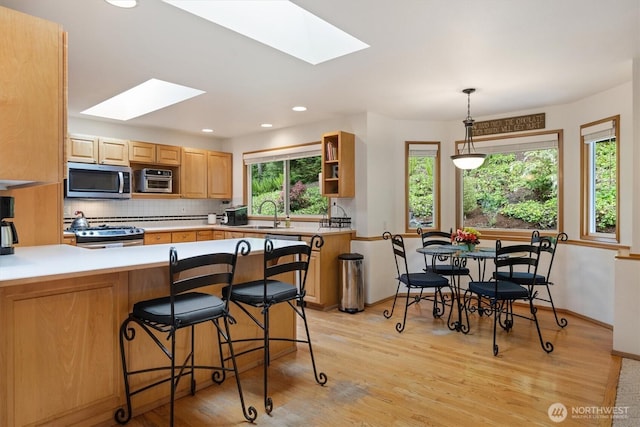 7123 NE 165th St, Kenmore, WA 98028 - kitchen with stainless steel appliances, a skylight, tasteful backsplash, a peninsula, and light wood-style floors
