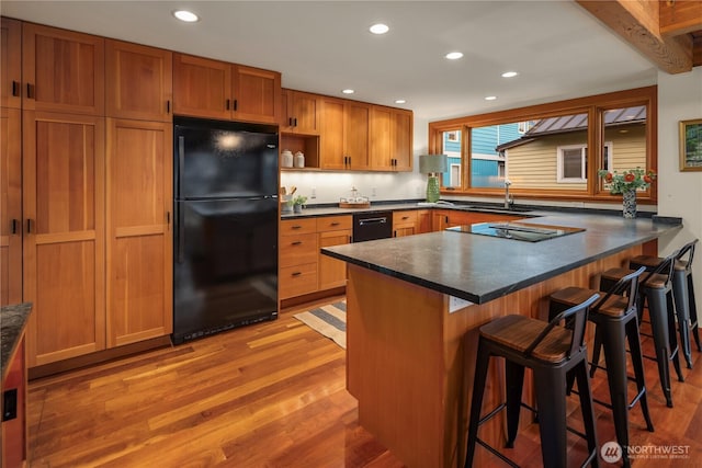 2339 Fairview Ave E Unit L, Seattle, WA 98102 - kitchen featuring black appliances, light wood-style floors, dark countertops, recessed lighting, and a peninsula