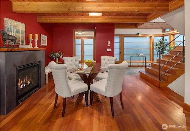 2339 Fairview Ave E Unit L, Seattle, WA 98102 - dining space featuring a wood ceiling with exposed beams, wood finished floors, stairs, a warm lit fireplace, and healthy amount of natural light