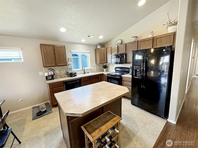 314 SW Homestead, College Place, WA 99324 - kitchen featuring black appliances, light countertops, healthy amount of natural light, a kitchen island, and a textured ceiling