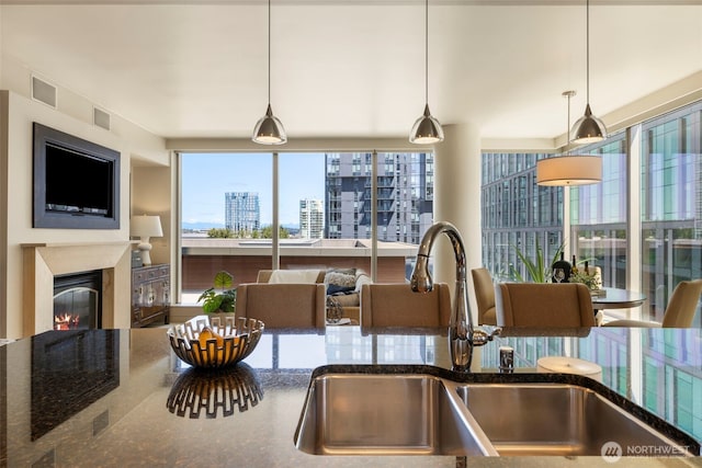 10610 NE 9th Pl Unit 1220, Bellevue, WA 98004 - kitchen featuring dark stone countertops, a glass covered fireplace, healthy amount of natural light, and hanging light fixtures