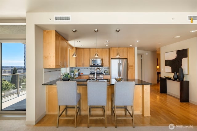 10610 NE 9th Pl Unit 1220, Bellevue, WA 98004 - kitchen with stainless steel appliances, a peninsula, light wood-type flooring, backsplash, and hanging light fixtures