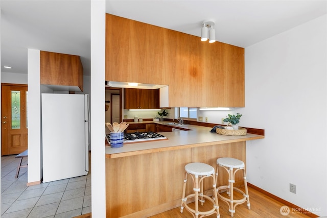 252 Myrtle St, Port Townsend, WA 98368 - kitchen with freestanding refrigerator, modern cabinets, a breakfast bar, brown cabinets, and light tile patterned floors
