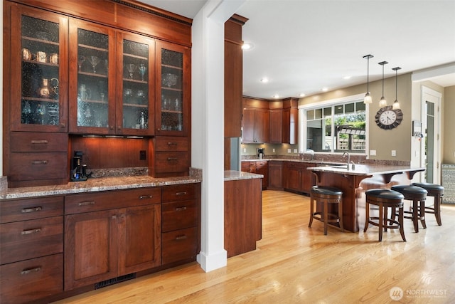 102 E Gibler Ln, Shelton, WA 98584 - kitchen with light wood-style flooring, a breakfast bar area, glass insert cabinets, hanging light fixtures, and a peninsula