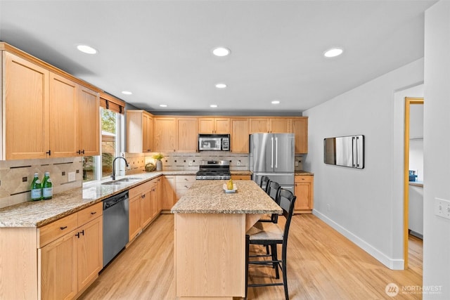 22418 SE 281st St, Maple Valley, WA 98038 - kitchen featuring appliances with stainless steel finishes, light brown cabinets, a kitchen breakfast bar, backsplash, and a center island