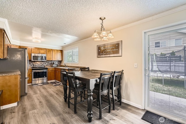 202 Elma Pl SE, Renton, WA 98059 - dining area with a textured ceiling, crown molding, a chandelier, and light wood-style floors