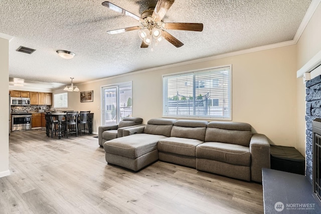 202 Elma Pl SE, Renton, WA 98059 - living room with ornamental molding, a stone fireplace, a textured ceiling, light wood-style flooring, and a ceiling fan
