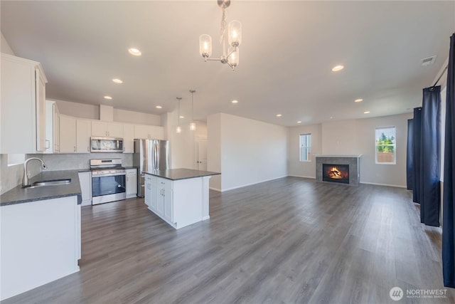514 Wellington Pl, Sedro Woolley, WA 98284 - kitchen featuring appliances with stainless steel finishes, dark countertops, white cabinets, dark wood-style flooring, and a kitchen island