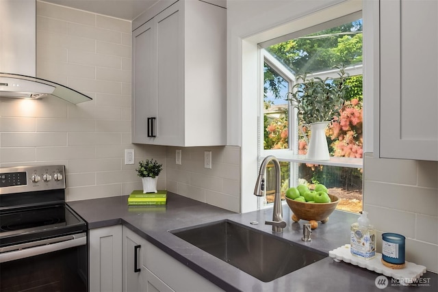 8046 40th Ave NE, Seattle, WA 98115 - kitchen featuring electric range, wall chimney exhaust hood, dark countertops, tasteful backsplash, and white cabinets