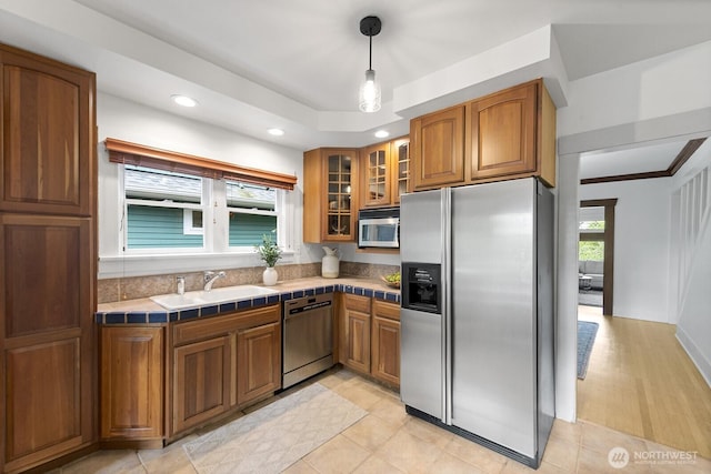 4628 Sunnyside Ave N, Seattle, WA 98103 - kitchen with appliances with stainless steel finishes, brown cabinets, tile counters, glass insert cabinets, and recessed lighting