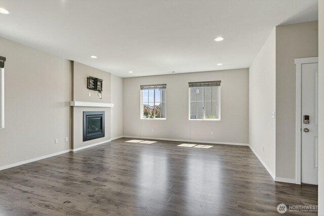 6729 283rd Pl NW, Stanwood, WA 98292 - unfurnished living room featuring a glass covered fireplace, wood finished floors, and recessed lighting