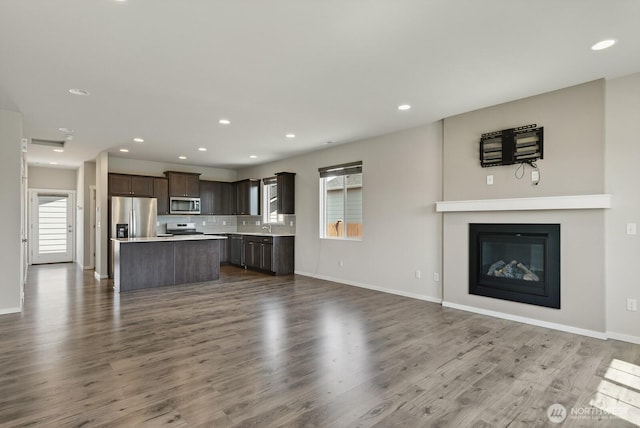 6729 283rd Pl NW, Stanwood, WA 98292 - unfurnished living room featuring dark wood-style floors, recessed lighting, and a glass covered fireplace