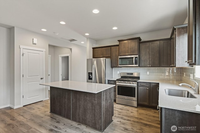 6729 283rd Pl NW, Stanwood, WA 98292 - kitchen with stainless steel appliances, dark brown cabinets, light wood-style floors, tasteful backsplash, and recessed lighting