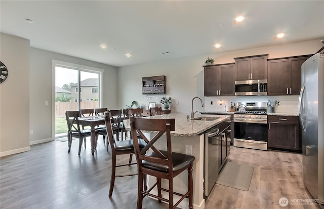7804 208th Ave E, Bonney Lake, WA 98391 - kitchen featuring stainless steel appliances, dark brown cabinets, light wood-style floors, a breakfast bar, and an island with sink