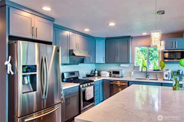 6601 27th Ln SE, Lacey, WA 98503 - kitchen with appliances with stainless steel finishes, under cabinet range hood, tasteful backsplash, light stone countertops, and decorative light fixtures