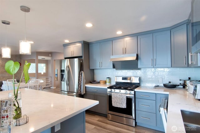 6601 27th Ln SE, Lacey, WA 98503 - kitchen with stainless steel appliances, under cabinet range hood, light stone counters, decorative backsplash, and decorative light fixtures