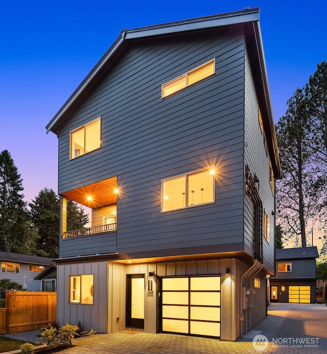 9047 Dibble Ave NW, Seattle, WA 98117 - view of front facade with board and batten siding, an attached garage, a balcony, and decorative driveway
