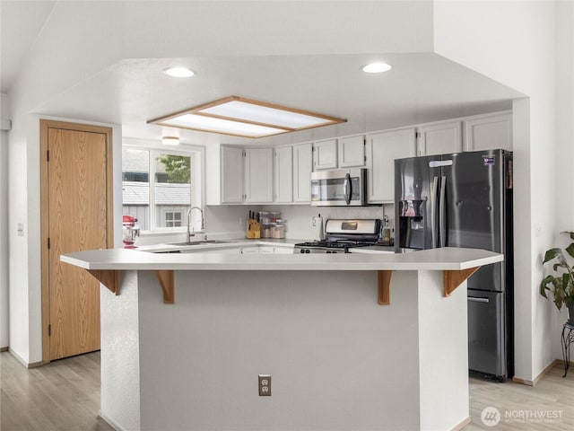 5415 Komachin Loop SE, Lacey, WA 98513 - kitchen with stainless steel appliances, light wood-style floors, light countertops, recessed lighting, and a kitchen bar