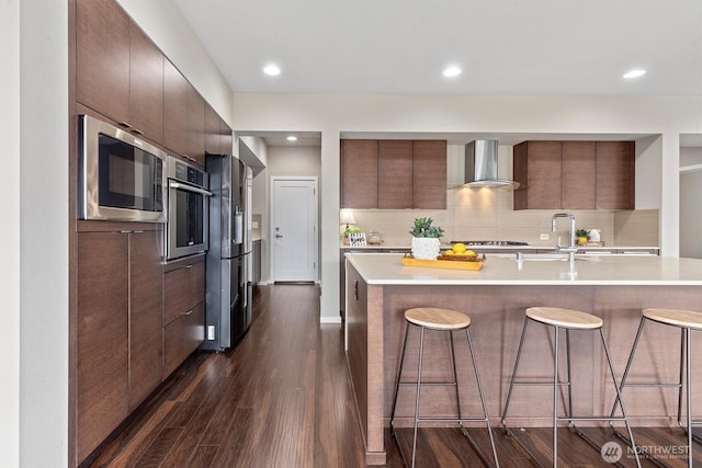 13506 196th Ave SE, Monroe, WA 98272 - kitchen with wall chimney exhaust hood, modern cabinets, appliances with stainless steel finishes, a breakfast bar area, and light countertops