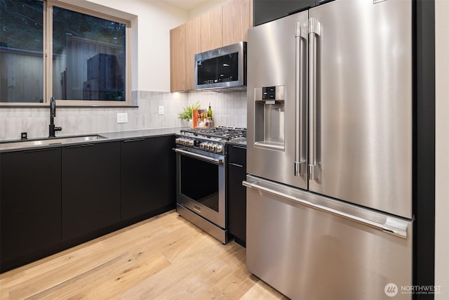 9047 Dibble Ave NW Unit C, Seattle, WA 98117 - kitchen featuring stainless steel appliances, modern cabinets, dark cabinetry, and light wood finished floors