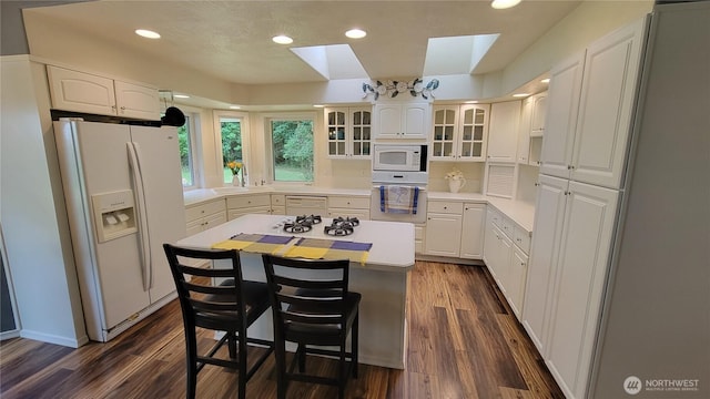 1225 98th Ln SE, Olympia, WA 98501 - kitchen featuring white appliances, a center island, a skylight, dark wood-style flooring, and a kitchen bar