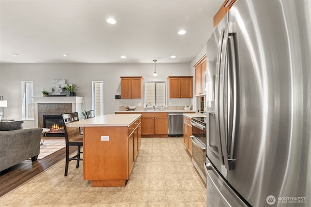 5611 Balustrade Blvd SE, Lacey, WA 98513 - kitchen with stainless steel appliances, open floor plan, a glass covered fireplace, a kitchen island, and light countertops