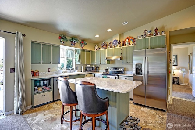 1985 Elhardt St, Camano Island, WA 98282 - kitchen with stainless steel appliances, green cabinetry, a center island, a breakfast bar, and under cabinet range hood