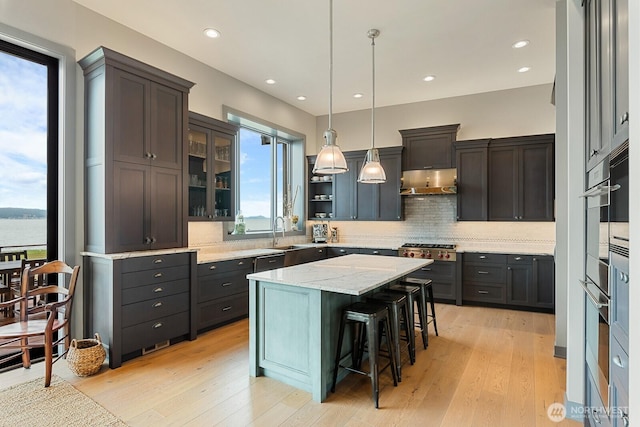 181 Utsalady Rd, Camano Island, WA 98282 - kitchen with tasteful backsplash, a kitchen bar, under cabinet range hood, hanging light fixtures, and a kitchen island