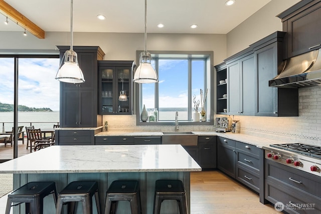 181 Utsalady Rd, Camano Island, WA 98282 - kitchen featuring under cabinet range hood, backsplash, a breakfast bar area, glass insert cabinets, and a center island