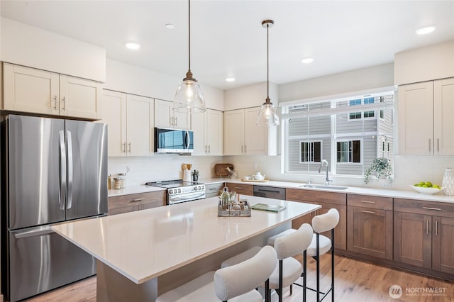 1322 194th St SE Unit H4, Bothell, WA 98012 - kitchen featuring stainless steel appliances, a breakfast bar, decorative backsplash, light countertops, and recessed lighting