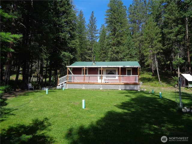 270 W Fork Rd, Conconully, WA 98819 - view of front facade with a front yard, a forest view, a wooden deck, and a metal roof