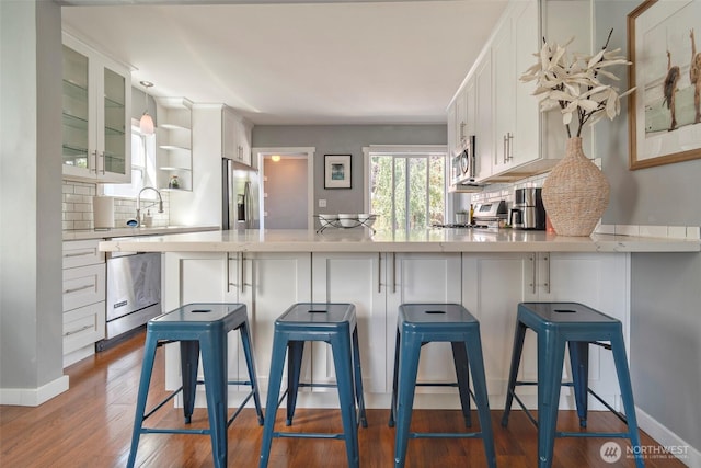 5253 35th Ave SW, Seattle, WA 98126 - kitchen featuring appliances with stainless steel finishes, light countertops, backsplash, glass insert cabinets, and white cabinets