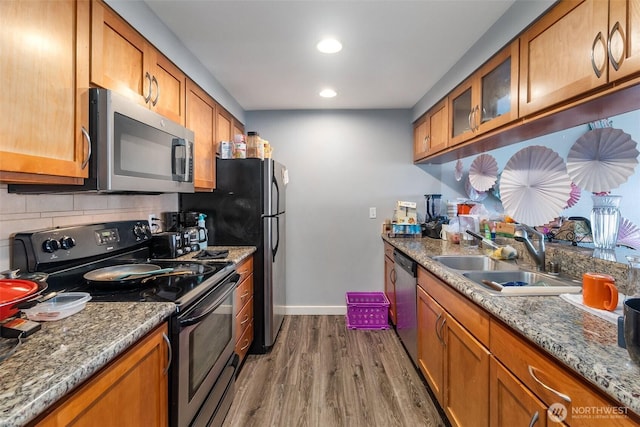 25 N Broadway Unit 207, Tacoma, WA 98403 - kitchen with stainless steel appliances, brown cabinets, wood finished floors, tasteful backsplash, and glass insert cabinets