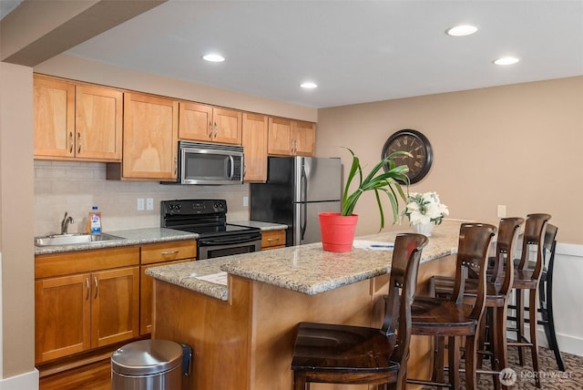 25 N Broadway Unit 207, Tacoma, WA 98403 - kitchen featuring appliances with stainless steel finishes, decorative backsplash, a breakfast bar, recessed lighting, and light stone countertops