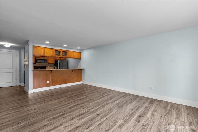 25 N Broadway Unit 207, Tacoma, WA 98403 - kitchen with freestanding refrigerator, stainless steel microwave, brown cabinetry, wood finished floors, and recessed lighting