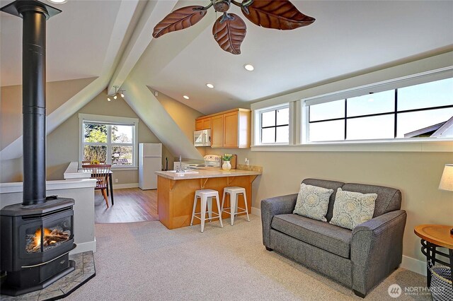 656 Lehman Dr, Camano Island, WA 98282 - kitchen with white appliances, a wood stove, a ceiling fan, a peninsula, and light carpet