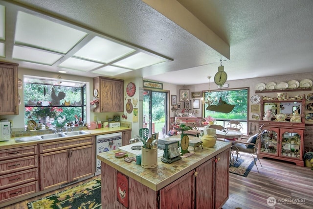 13273 W Cloquallum Rd, Elma, WA 98541 - kitchen featuring dishwashing machine, a textured ceiling, wood finished floors, a kitchen island, and healthy amount of natural light