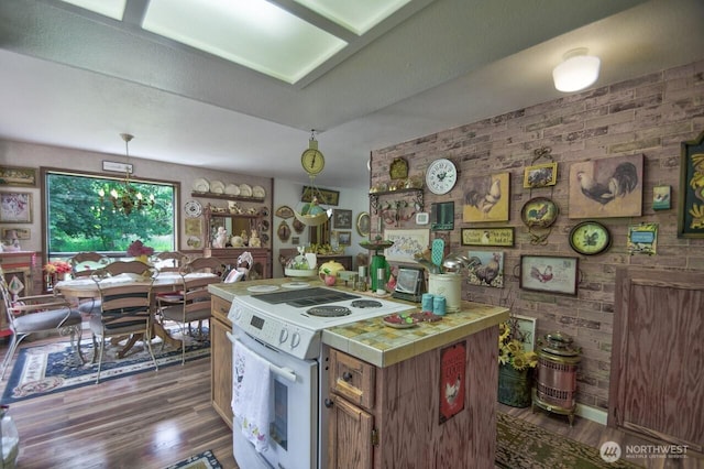 13273 W Cloquallum Rd, Elma, WA 98541 - kitchen with tile countertops, electric stove, wood finished floors, brick wall, and brown cabinetry
