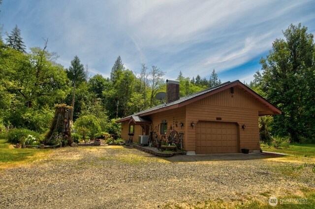 13273 W Cloquallum Rd, Elma, WA 98541 - view of side of home featuring a chimney, a garage, and dirt driveway