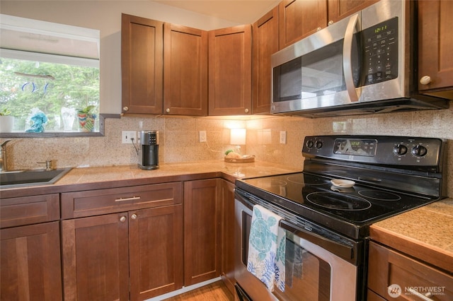 755 Island Cir SE, Ocean Shores, WA 98569 - kitchen featuring appliances with stainless steel finishes, light countertops, decorative backsplash, and brown cabinets