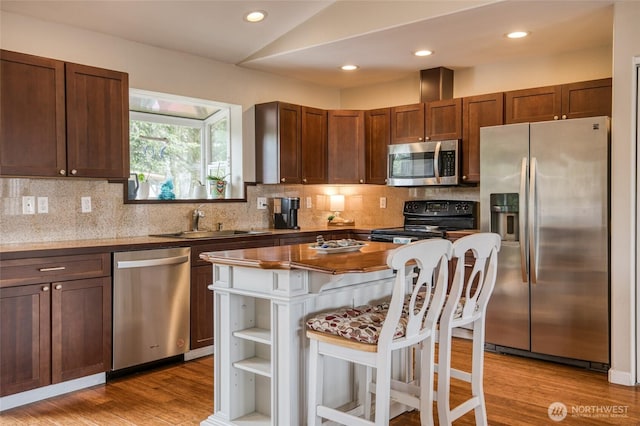 755 Island Cir SE, Ocean Shores, WA 98569 - kitchen with appliances with stainless steel finishes, lofted ceiling, decorative backsplash, a kitchen breakfast bar, and light wood-style flooring