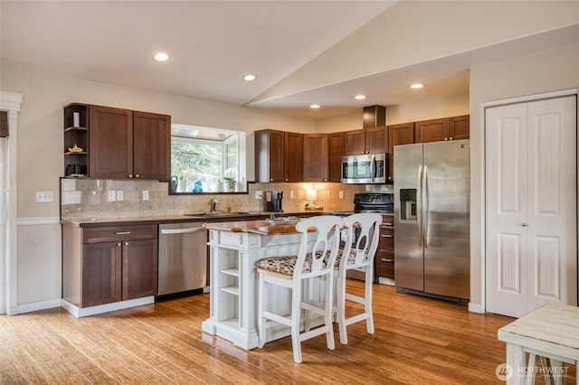 755 Island Cir SE, Ocean Shores, WA 98569 - kitchen featuring stainless steel appliances, open shelves, vaulted ceiling, decorative backsplash, and a kitchen breakfast bar